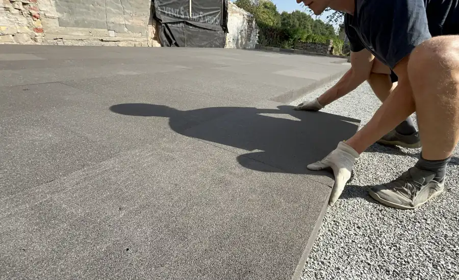 Arbeiter trägt eine Abdichtungsschicht auf eine Betonbodenplatte auf