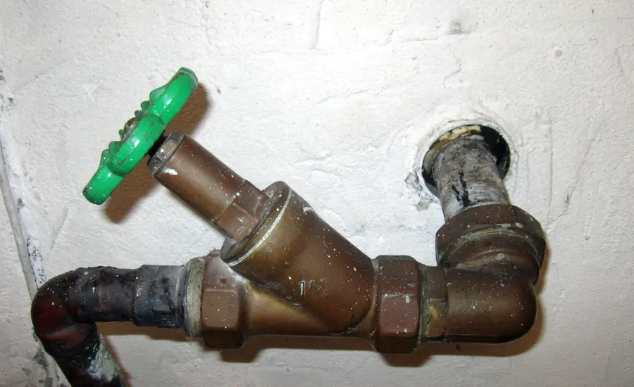 Absperrventil mit grünem Griff an einer Wasserleitung in der Hauseinführung