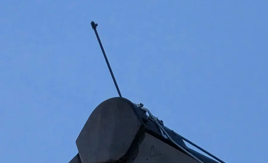 Fangstange eines Blitzableiters auf einem Dachaufbau vor blauem Himmel