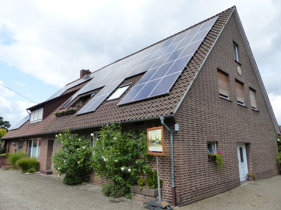 Wohnhaus aus rotem Klinker mit Photovoltaikmodulen auf der Dachfläche (Symbolfoto)