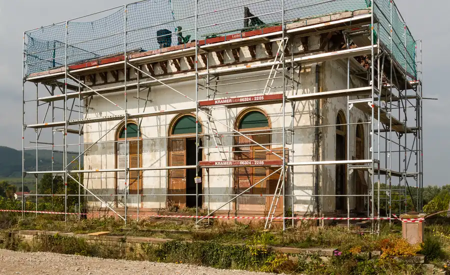 Eingerüstetes Altbaugebäude mit verwitterter Putzfassade und Rundbogenfenstern während der Sanierung