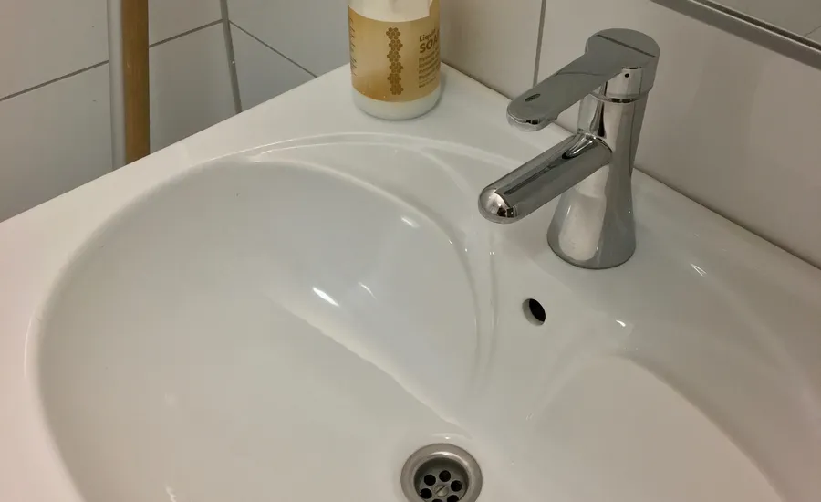 Verchromte Einhebelarmatur an einem weißen Waschbecken vor Wandfliesen