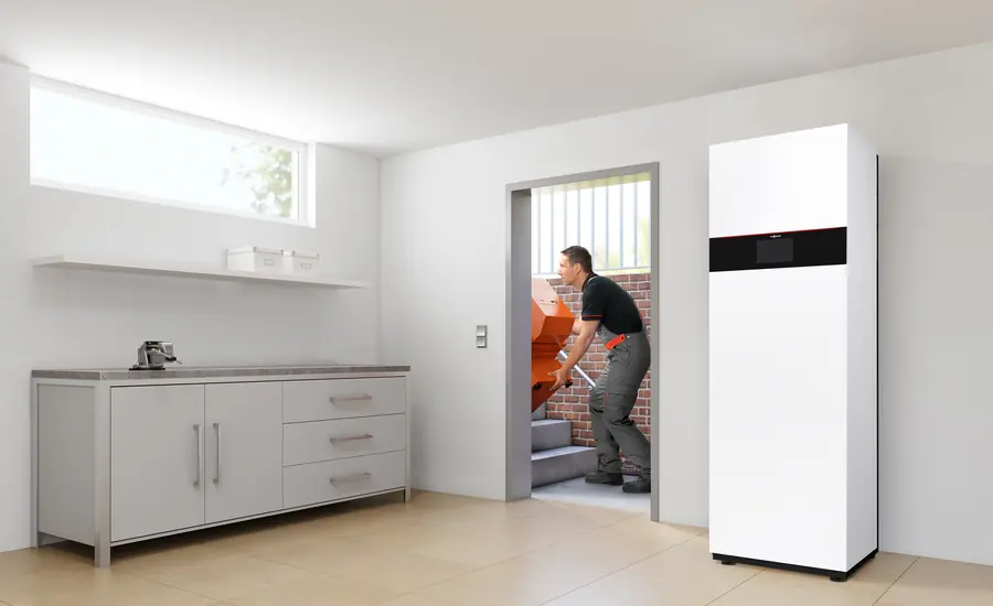 Wärmepumpen-Inneneinheit in einem hellen Hauswirtschaftsraum, im Hintergrund ein Installateur
