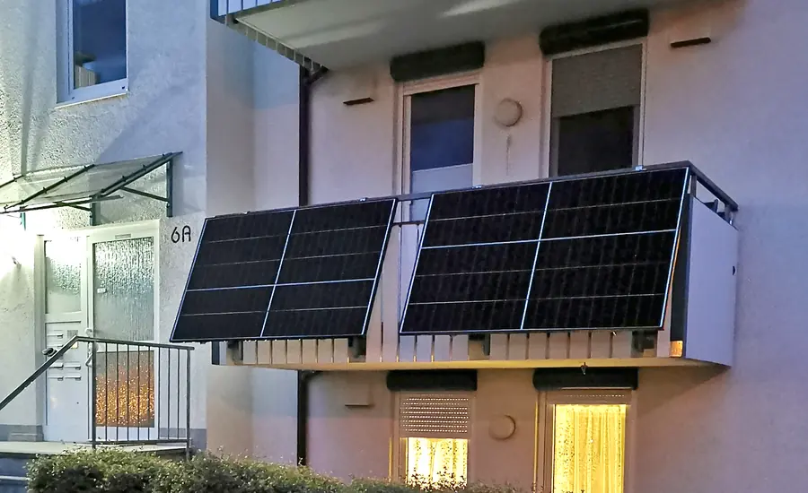 Vier Solarmodule an der Balkonbrüstung eines Mehrfamilienhauses
