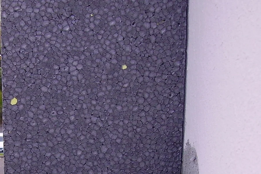 Graue Dämmplatten an einer Gebäudefassade neben einer verputzten Wand