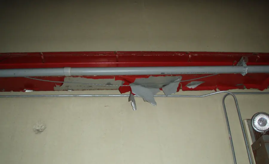 Abblätternder alter Anstrich an einem rot gestrichenen Deckenträger