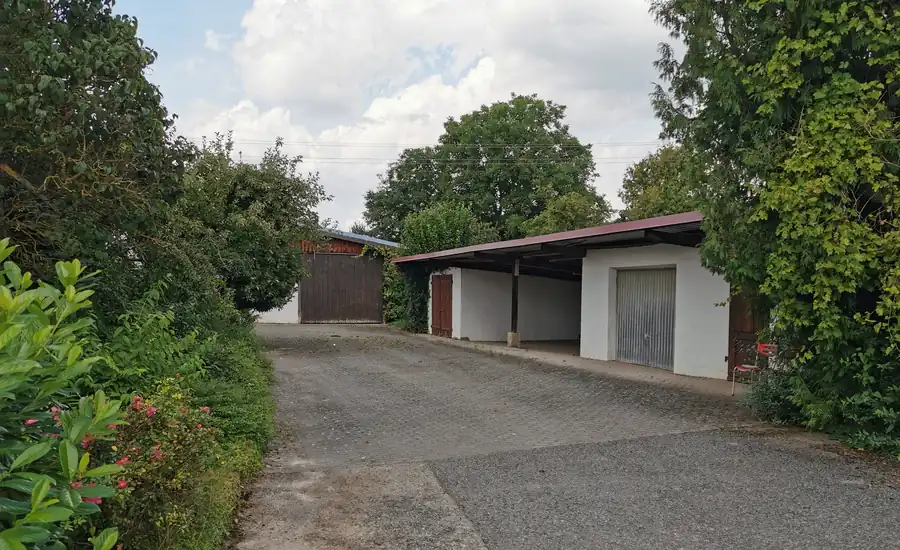 Offener Carport neben einer geschlossenen Garage an einer Zufahrt