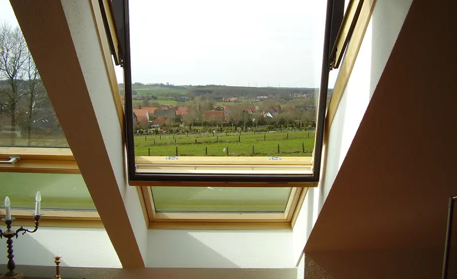 Geöffnetes Dachfenster mit Holzlaibung und Blick über Felder