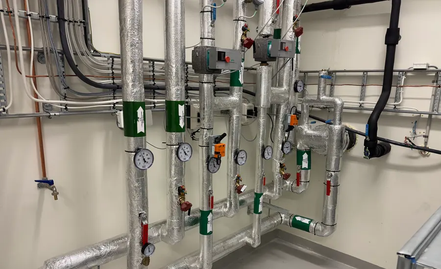 Heizungsverteiler im Technikraum mit Pumpen, Absperrhähnen und Manometern