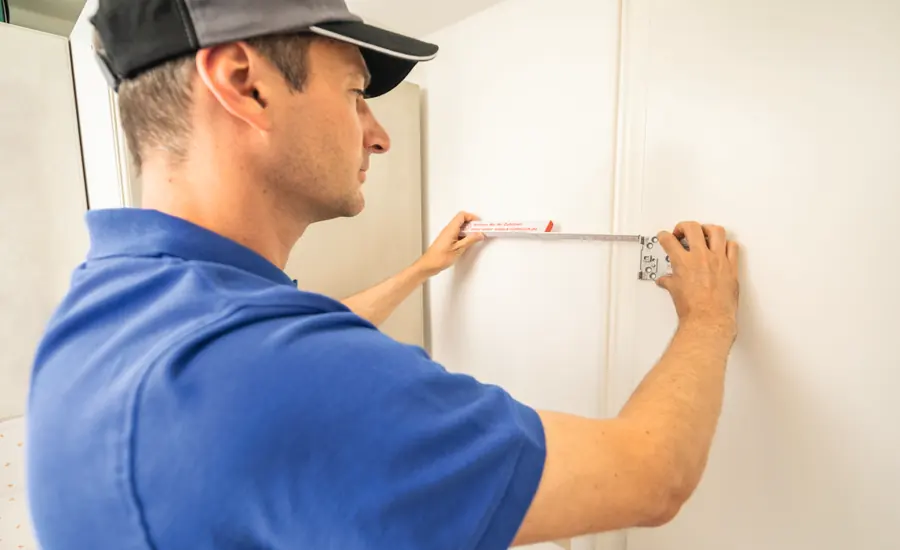 Handwerker misst mit einem Zollstock eine Position an der Wand für die Montage aus