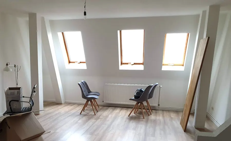 Leere Dachgeschosswohnung mit drei Dachflächenfenstern und Heizkörpern