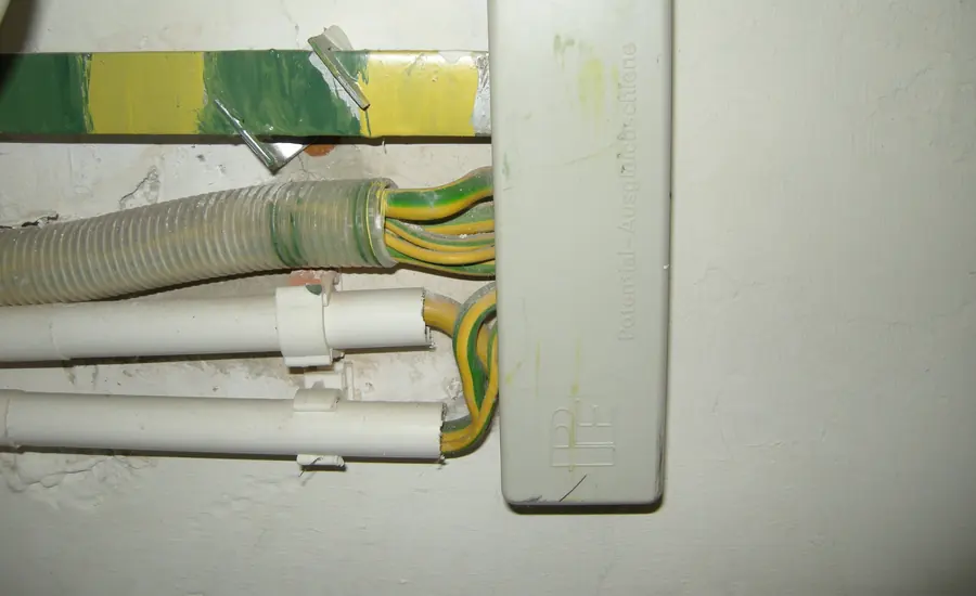 Potentialausgleichsschiene mit grün-gelben Erdungsleitern an einer Wand