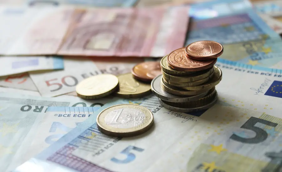 Euro-Geldscheine auf einer Fläche, darauf gestapelte Euro-Münzen