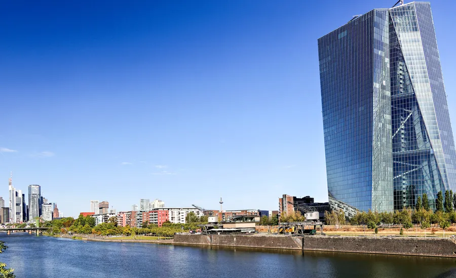 Das gläserne Hochhaus der Europäischen Zentralbank im Frankfurter Ostend am Mainufer, links im Hintergrund die Frankfurter Bankentürme unter blauem Himmel