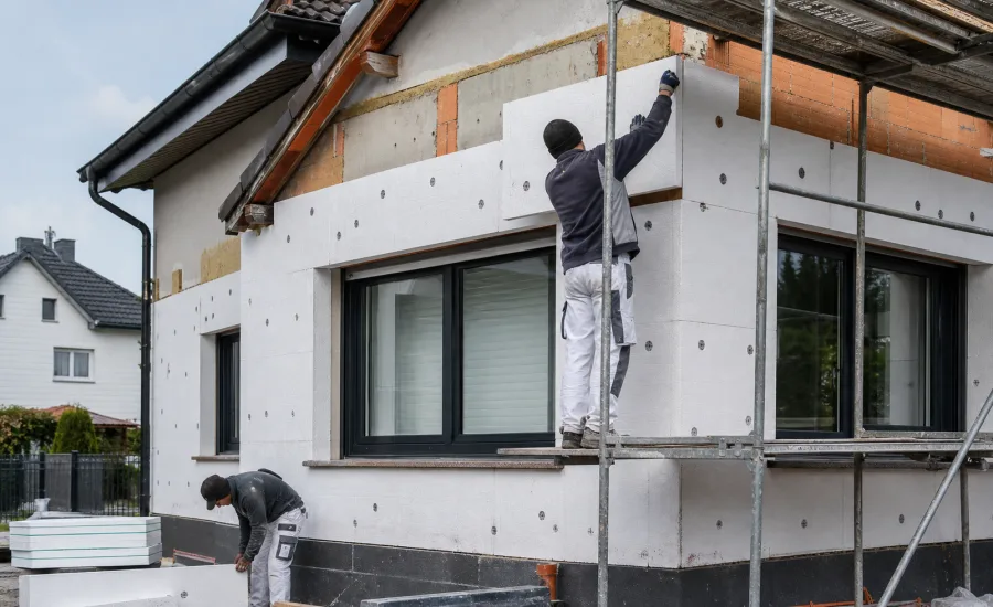 Handwerker montieren Dämmplatten an einer Hausfassade – was die Fassadendämmung kostet