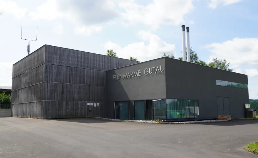 Dunkles Heizwerksgebäude mit dem Schriftzug Fernwärme Gutau und zwei Schornsteinen