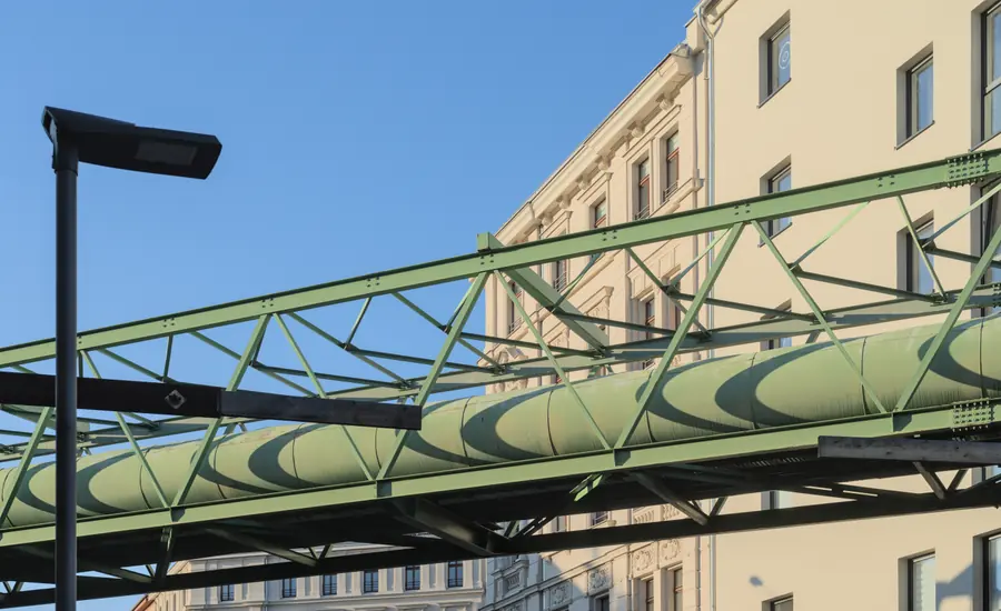 Grün gestrichene Fernwärmeleitung auf einer Stahlbrücke über einer Straße