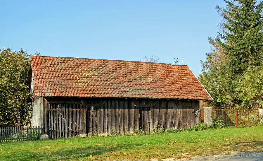 Älterer Holzschuppen mit Ziegeldach am Rand einer Wiese