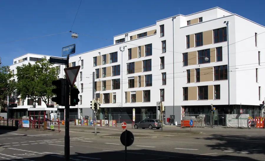 Neu gebaute weiße Mehrfamilienhäuser mit Balkonen und großen Fenstern an einer Straßenkreuzung in Freiburg