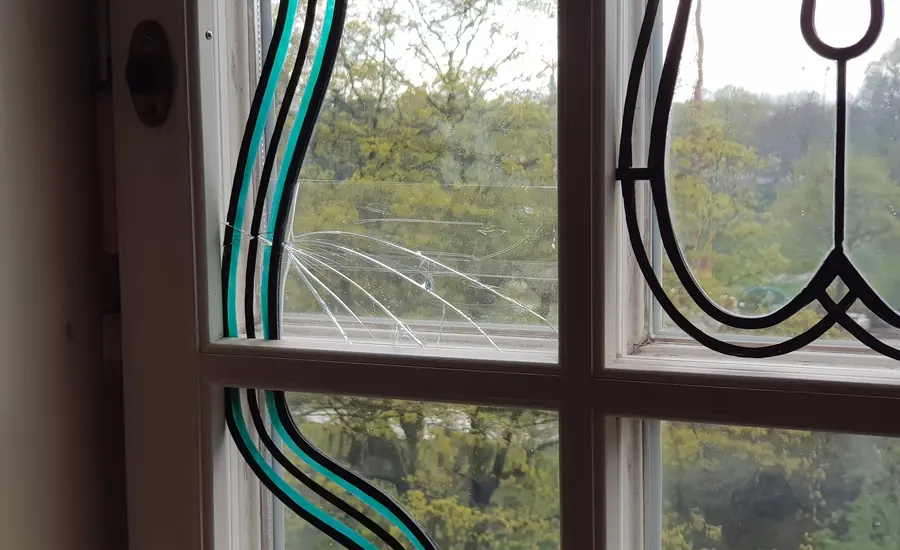 Fensterscheibe mit sternförmigem Sprung in einem Holzfenster