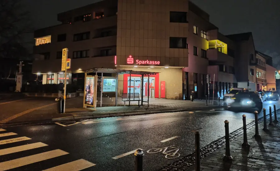 Beleuchtete Sparkassen-Filiale mit rotem Logo im Erdgeschoss eines Eckgebäudes am Magdalenenplatz in Bonn bei Nacht