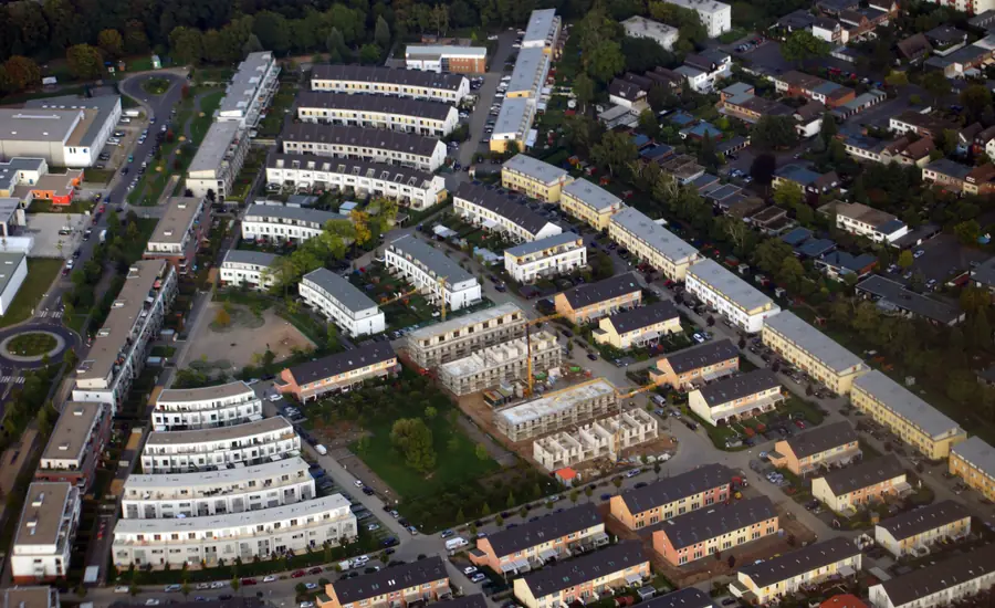Luftaufnahme des Neubaugebiets Merheimer Gärten in Köln mit Reihenhauszeilen, Mehrfamilienhäusern und Rohbauten, dahinter ältere Einfamilienhäuser