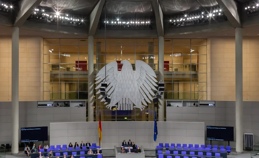Plenarsaal des Deutschen Bundestages im Reichstagsgebäude: Bundesadler vor der Glaswand, darunter Präsidium, Regierungsbank und blaue Abgeordnetensitze
