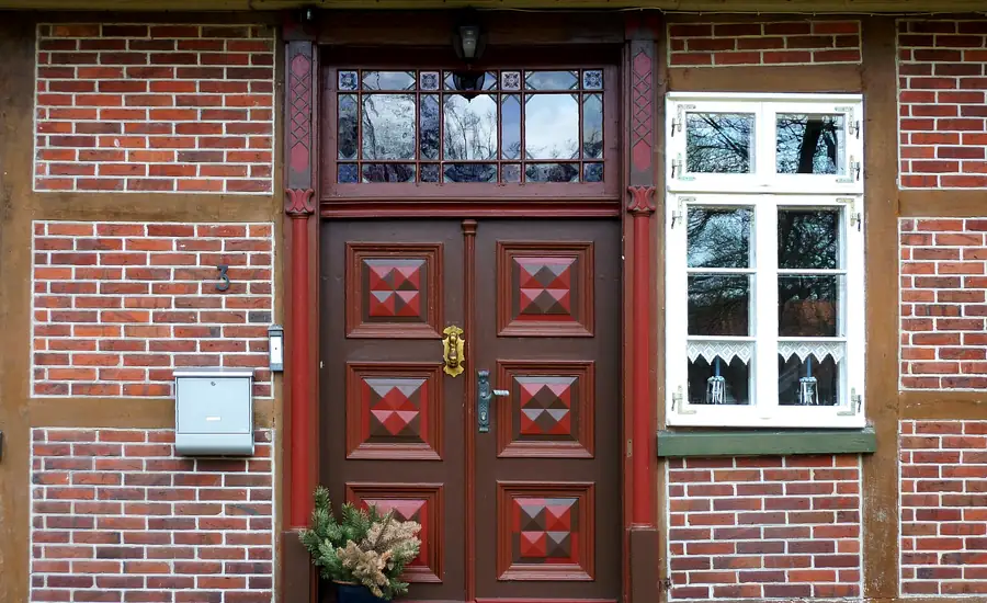 Dunkelrote Holzhaustür mit Glaseinsatz in einer Klinkerfassade