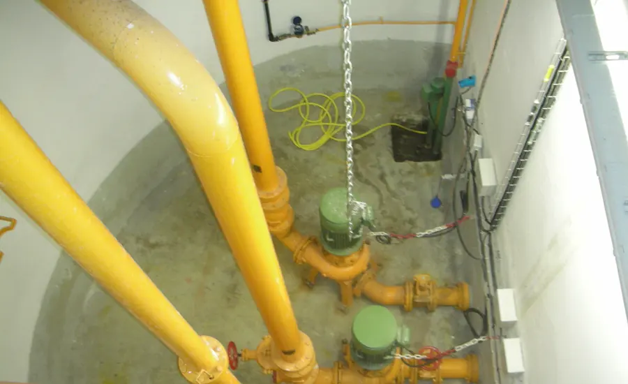 Pumpenschacht einer Abwasserhebeanlage mit gelben Druckleitungen