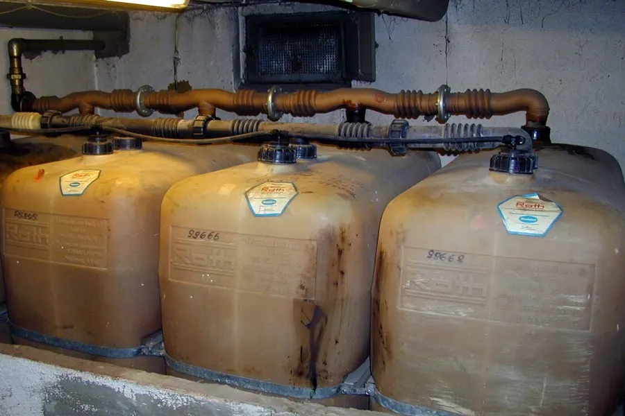 Vier Kunststofftanks für Heizöl stehen nebeneinander in einem Kellerraum, oben durch Leitungen verbunden (Symbolbild)