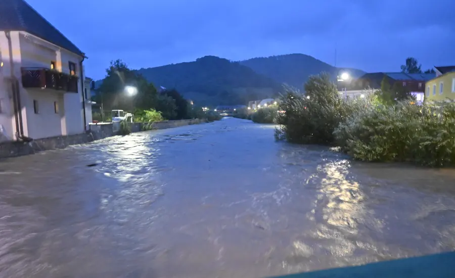 Hochwasser fuehrender Fluss zwischen Wohnhaeusern eines Ortes in der Daemmerung