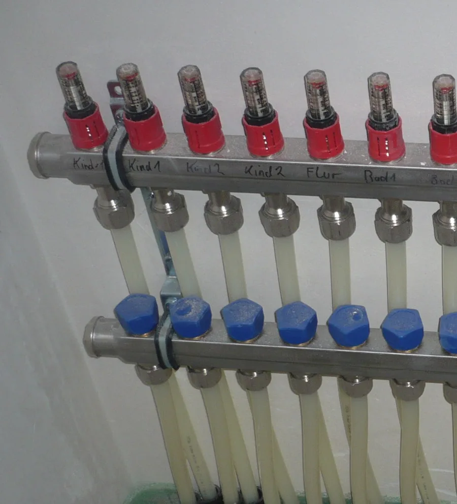 Heizkreisverteiler mit transparenten Durchflussanzeigen, roten Einstellringen und blauen Ventilkappen