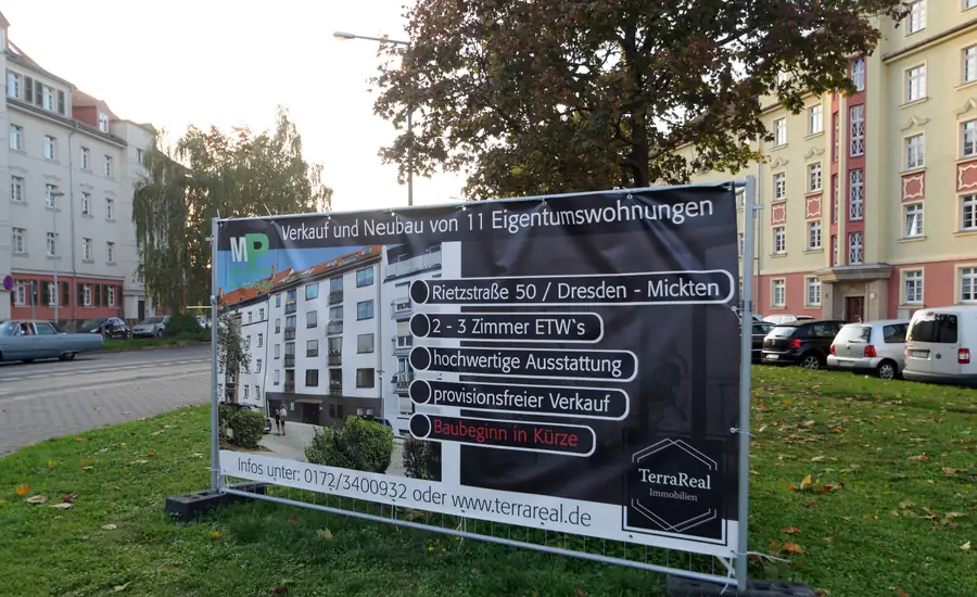 Werbebanner auf einer Rasenfläche in Dresden-Mickten, das den Verkauf von elf neu gebauten Eigentumswohnungen mit Visualisierung und Stichpunkten bewirbt