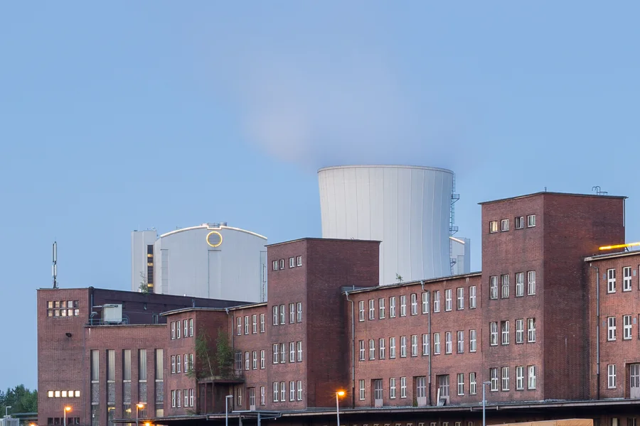 Rote Backstein-Fabrikgebäude mit hellen technischen Aufbauten in der Abenddämmerung.