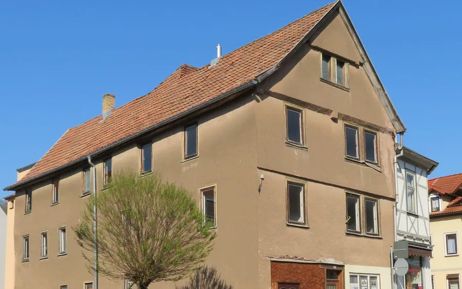 Älteres Wohnhaus mit Ziegeldach, abgenutzter Putzfassade und Holzfenstern