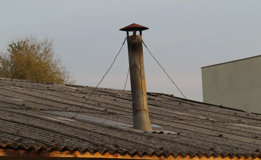 Schornstein mit Regenhaube und Abspannung auf einem Hausdach