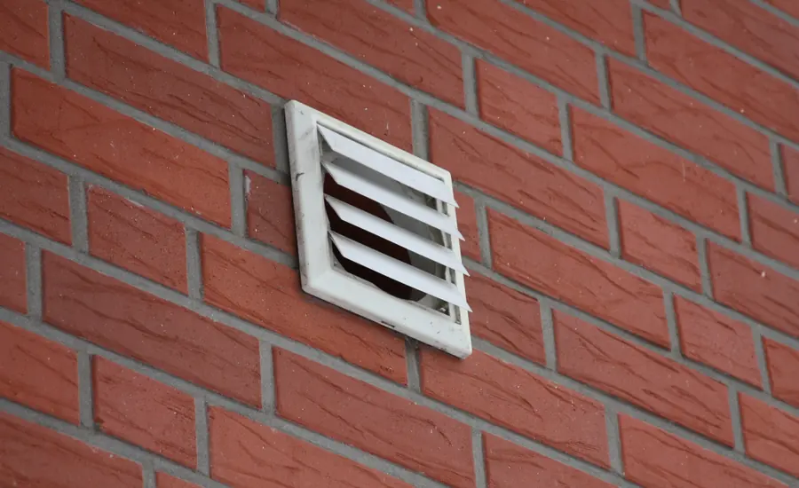 Weißes Lüftungsgitter in einer roten Klinkerfassade
