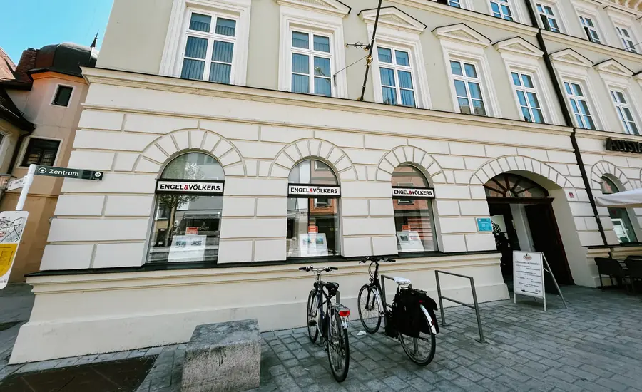 Immobilienbüro im Erdgeschoss eines Geschäftshauses in der Freisinger Altstadt, in den Bogenfenstern hängen Objektangebote aus