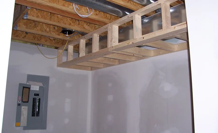 Unverkleidete Deckenkonstruktion aus Holz mit Luftkanal und Verteilerkasten an der Wand