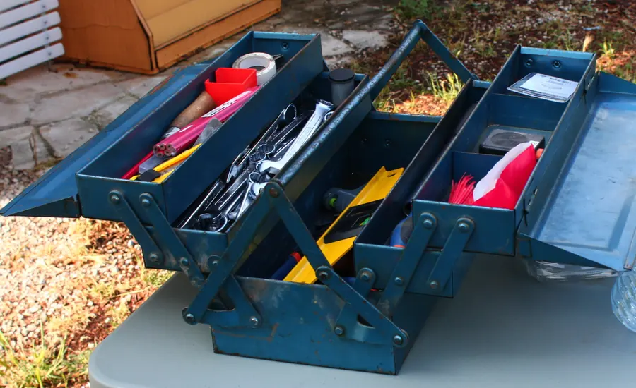 Geöffneter blauer Werkzeugkasten mit Zangen, Schraubendrehern und Kleinteilen