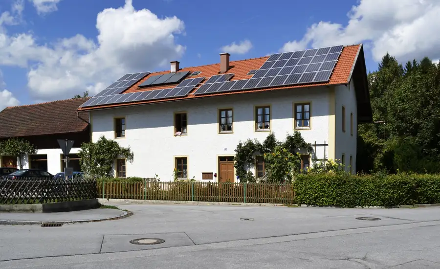 Wohnhaus mit Satteldach, auf dem mehrere Felder mit Photovoltaikmodulen montiert sind