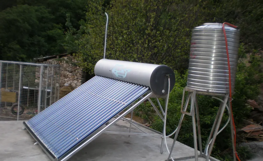 Solarer Röhrenkollektor neben einem stehenden Edelstahl-Wasserspeicher im Freien
