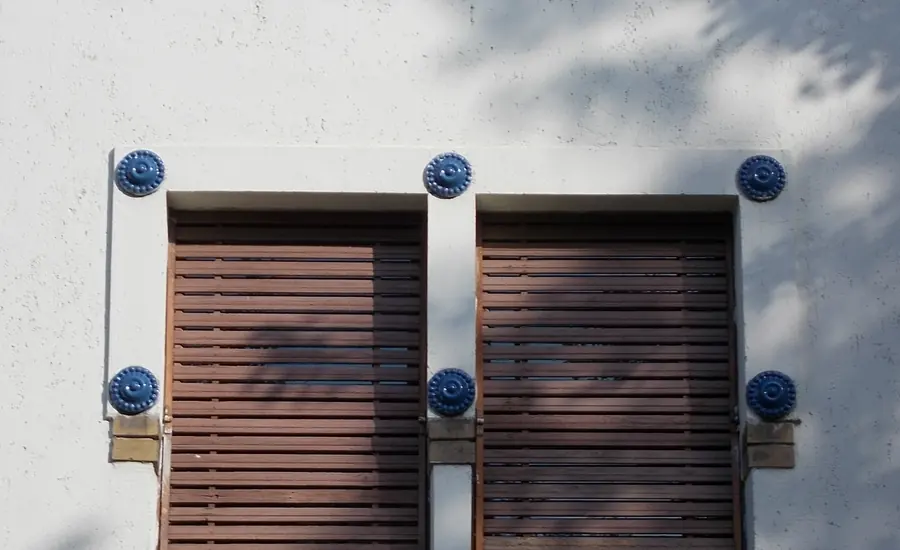 Zwei geschlossene braune Rollläden an einer hellen Hausfassade