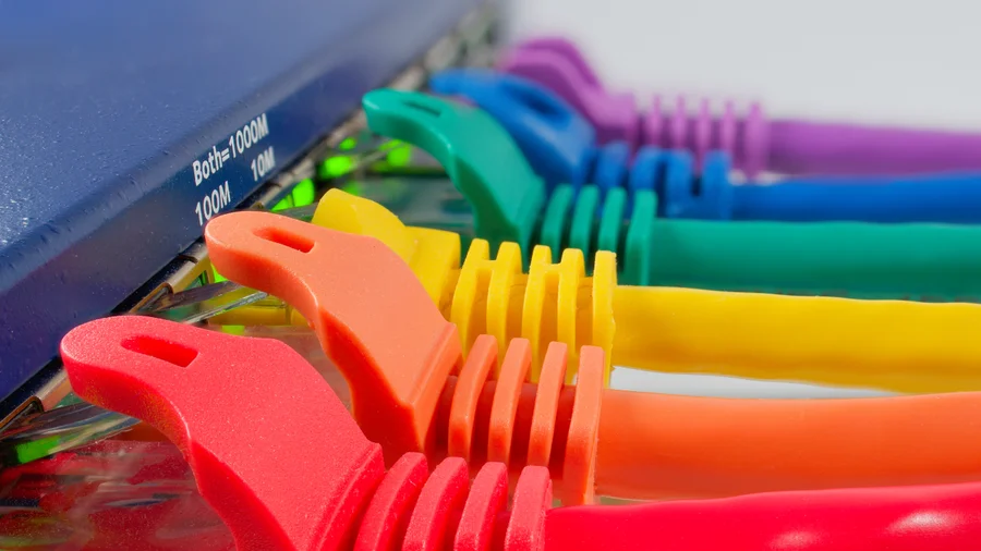 Bunte Ethernetkabel in den Buchsen eines Netzwerkgeräts mit leuchtenden Statusanzeigen