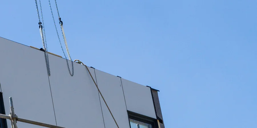 Vorgefertigtes Fassadenelement mit Fenster an den Ketten eines Krans