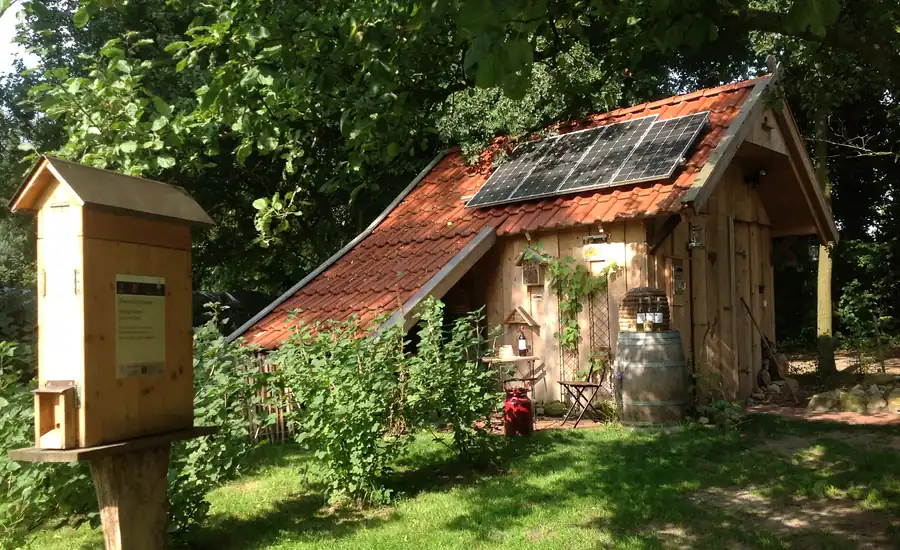 Kleine Scheune mit Solarmodulen auf dem Ziegeldach in einem Garten