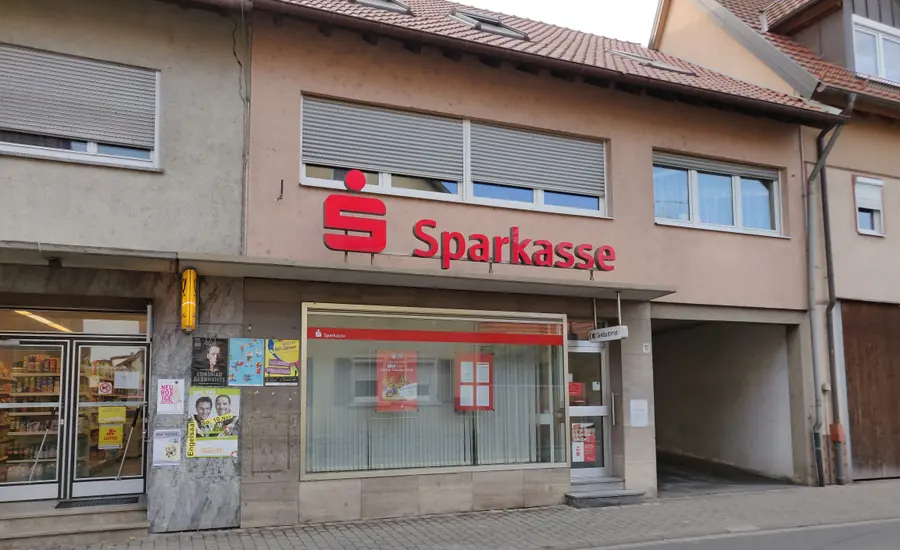 Filiale der Sparkasse Tauberfranken in Werbach mit rotem Sparkassen-Schriftzug über dem Schaufenster und einer Toreinfahrt daneben