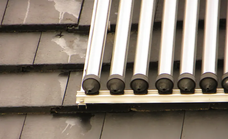 Vakuumröhrenkollektor einer thermischen Solaranlage auf einem dunklen Dach aus Schieferplatten