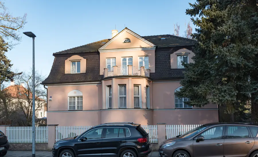 Wohnhaus mit Mansarddach an einer Straße mit parkenden Autos