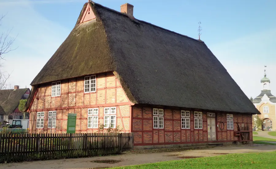 Reetgedecktes Fachwerkhaus mit roten Ziegelgefachen und weißen Sprossenfenstern, ein Altenteilerhaus aus Negenharrie im Schleswig-Holsteinischen Freilichtmuseum.